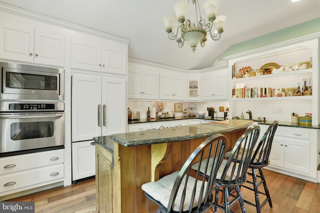 2538 Church Ln, Doylestown, PA 18902 - kitchen featuring appliances with stainless steel finishes, lofted ceiling, white cabinetry, a chandelier, and a kitchen bar