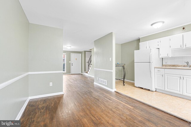 5649 Kavon Ave, Baltimore, MD 21206 - kitchen with freestanding refrigerator, a sink, light countertops, light wood-type flooring, and white cabinetry