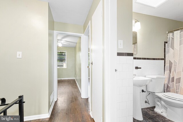 5649 Kavon Ave, Baltimore, MD 21206 - bathroom featuring toilet, ceiling fan, tile walls, wood finished floors, and a wainscoted wall