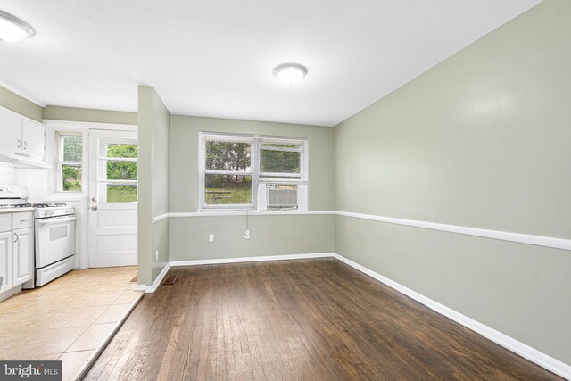 5649 Kavon Ave, Baltimore, MD 21206 - kitchen with white gas range oven, under cabinet range hood, hardwood / wood-style floors, white cabinetry, and baseboards