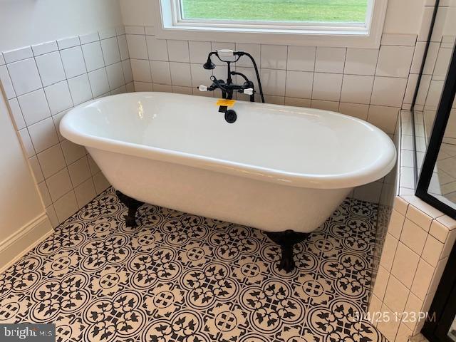 31123 Surfbird Way, Millsboro, DE 19966 - bathroom featuring healthy amount of natural light, tile walls, a freestanding bath, and tile patterned flooring