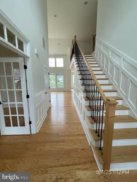 31123 Surfbird Way, Millsboro, DE 19966 - stairway with a towering ceiling, a decorative wall, wood finished floors, and a wainscoted wall