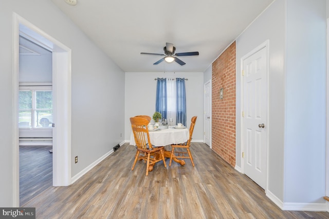 1267 Dominion Rd, Gerrardstown, WV 25420 - dining area featuring brick wall, wood finished floors, a ceiling fan, and baseboards