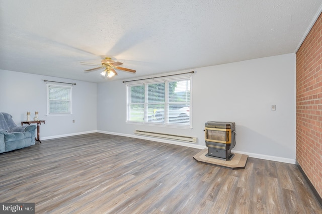 1267 Dominion Rd, Gerrardstown, WV 25420 - unfurnished living room featuring a baseboard heating unit, a ceiling fan, brick wall, a wood stove, and wood finished floors