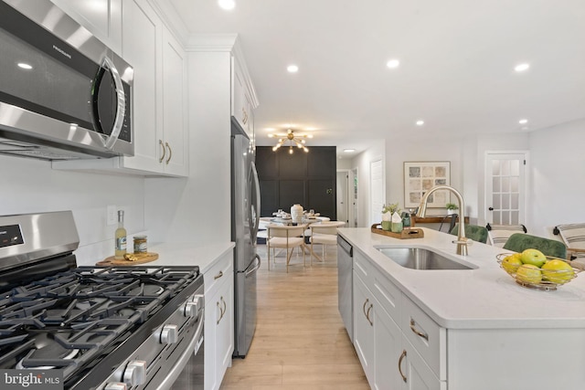 112 Morris Ave, Woodlyn, PA 19094 - kitchen featuring appliances with stainless steel finishes, a sink, light wood-type flooring, white cabinets, and a center island with sink