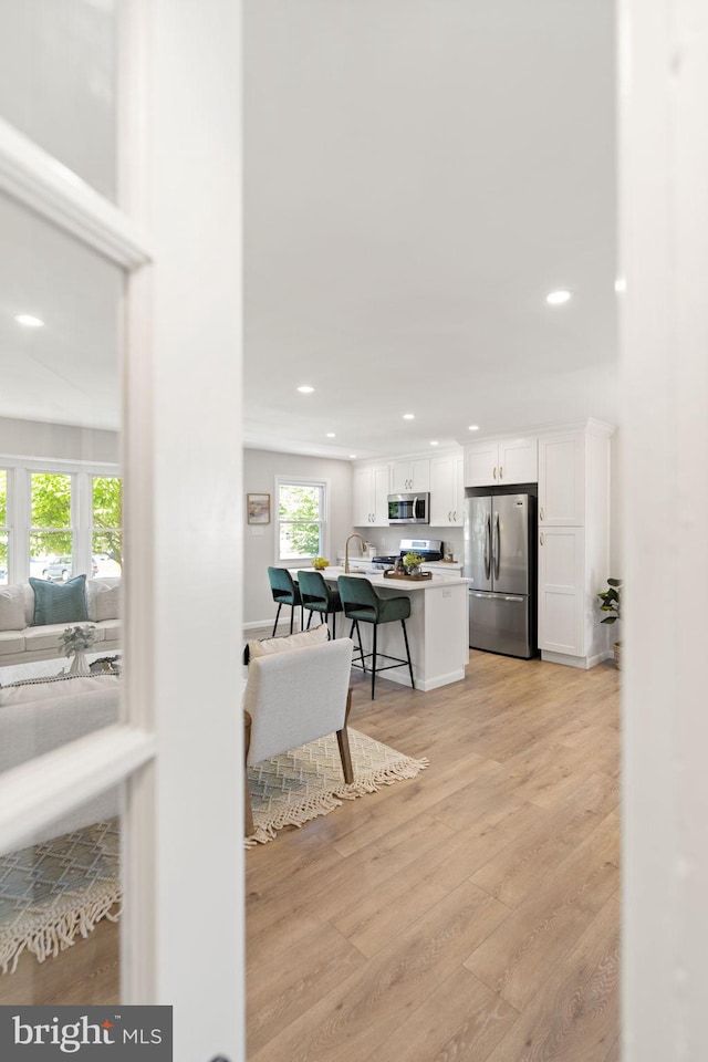 112 Morris Ave, Woodlyn, PA 19094 - kitchen with appliances with stainless steel finishes, white cabinets, light wood finished floors, recessed lighting, and a breakfast bar