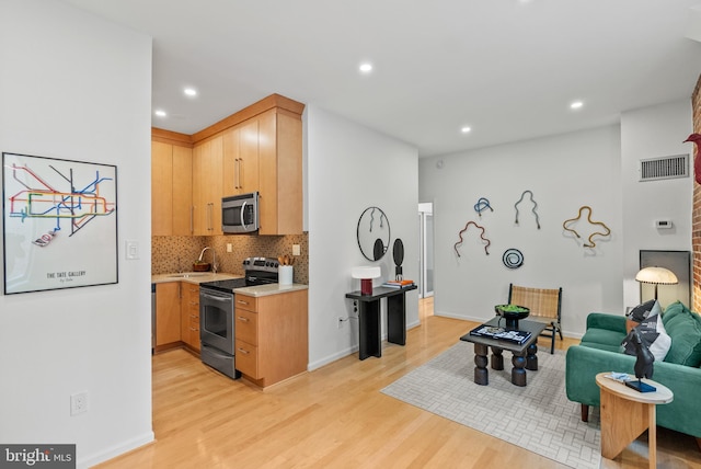 1615 Q St NW Unit 214, Washington, DC 20009 - kitchen with stainless steel appliances, light countertops, light wood-style flooring, backsplash, and recessed lighting