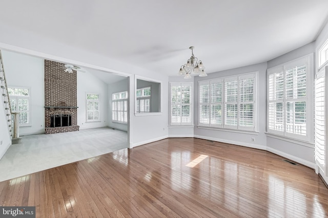 10106 Waterside Dr, Burke, VA 22015 - unfurnished living room featuring a chandelier, wood-type flooring, a brick fireplace, and baseboards