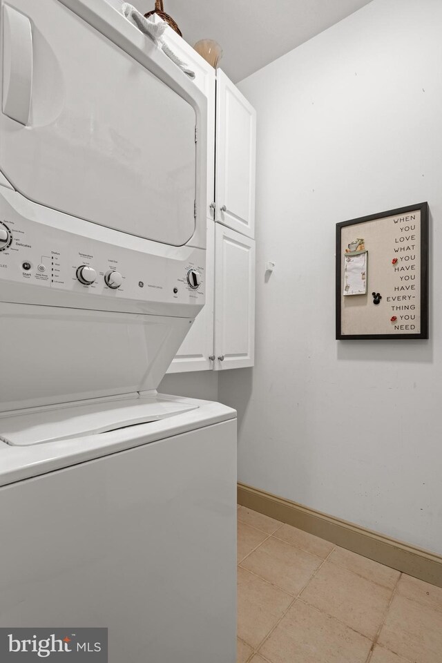 66 Farmview Ln, Lititz, PA 17543 - laundry room with stacked washer / drying machine, cabinet space, baseboards, and light tile patterned floors