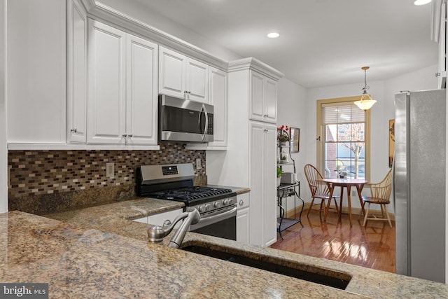 66 Farmview Ln, Lititz, PA 17543 - kitchen with appliances with stainless steel finishes, wood finished floors, tasteful backsplash, white cabinetry, and light stone countertops
