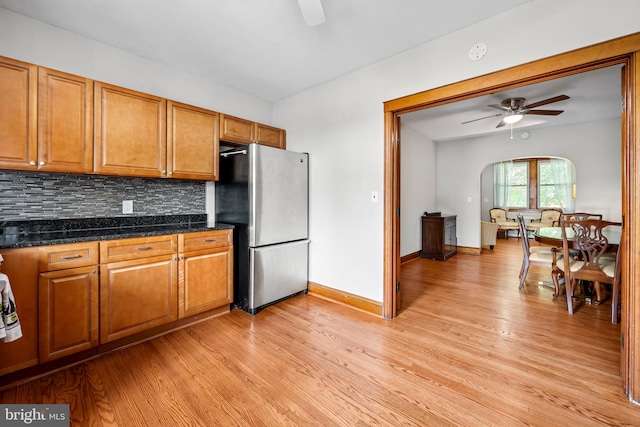 434 Elrino St, Baltimore, MD 21224 - kitchen with freestanding refrigerator, ceiling fan, arched walkways, brown cabinets, and light wood-style flooring