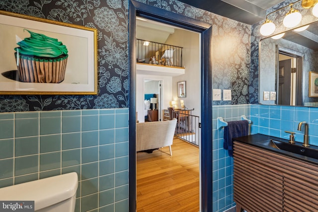 1011 Dickinson St, Philadelphia, PA 19147 - bathroom featuring wallpapered walls, tile walls, wood finished floors, toilet, and a wainscoted wall