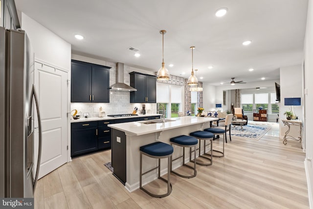 6411 Tulip Ter, Haymarket, VA 20169 - kitchen featuring stainless steel appliances, a sink, wall chimney range hood, a kitchen breakfast bar, and light countertops