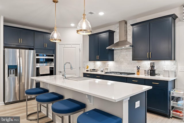 6411 Tulip Ter, Haymarket, VA 20169 - kitchen featuring appliances with stainless steel finishes, wall chimney exhaust hood, backsplash, a kitchen bar, and light wood-type flooring