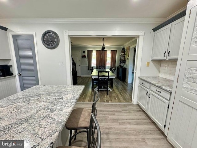 159 Harwich St, Browns Mills, NJ 08015 - kitchen with crown molding, light wood finished floors, light stone countertops, a kitchen bar, and tasteful backsplash