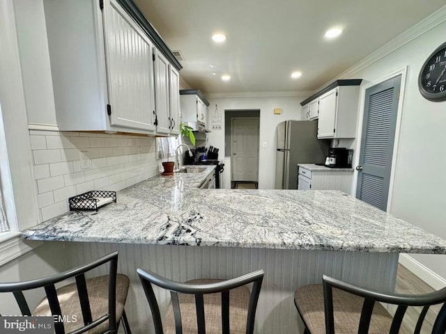 159 Harwich St, Browns Mills, NJ 08015 - kitchen featuring freestanding refrigerator, a peninsula, ornamental molding, tasteful backsplash, and a breakfast bar