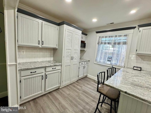 159 Harwich St, Browns Mills, NJ 08015 - kitchen with crown molding, decorative backsplash, baseboards, light wood-type flooring, and light stone countertops