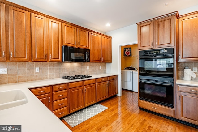 256 Silverbell Ct, West Chester, PA 19380 - kitchen featuring black appliances, washer and dryer, light countertops, brown cabinets, and tasteful backsplash
