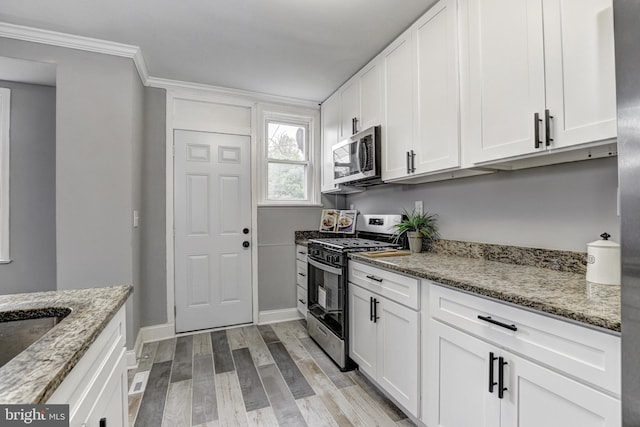 2503 W Forest Park Ave, Baltimore, MD 21215 - kitchen with stainless steel appliances, light wood-style flooring, white cabinetry, and crown molding