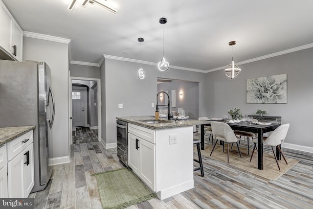 2503 W Forest Park Ave, Baltimore, MD 21215 - kitchen featuring stainless steel appliances, a sink, a center island with sink, light wood finished floors, and white cabinetry
