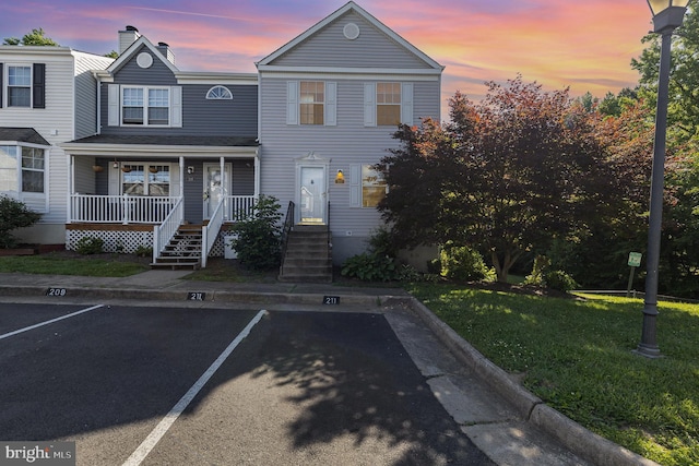 211 Westminster Ln Unit 119, Stafford, VA 22556 - view of property featuring uncovered parking, covered porch, a front yard, and a chimney