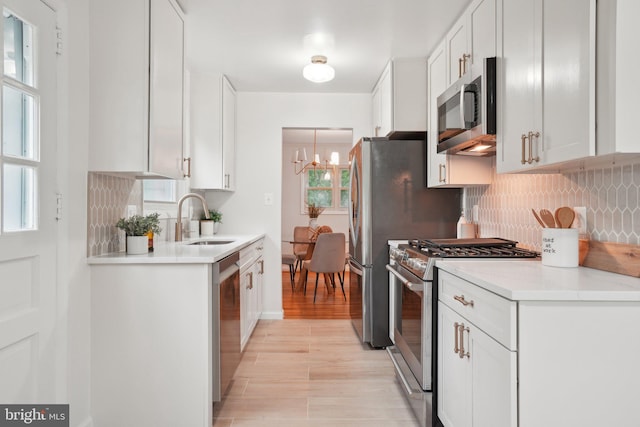 12834 Littleton St, Silver Spring, MD 20906 - kitchen with stainless steel appliances, a sink, decorative backsplash, a chandelier, and white cabinetry