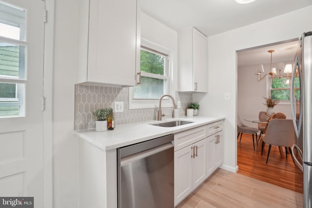 12834 Littleton St, Silver Spring, MD 20906 - kitchen featuring stainless steel appliances, a sink, a chandelier, decorative backsplash, and white cabinets