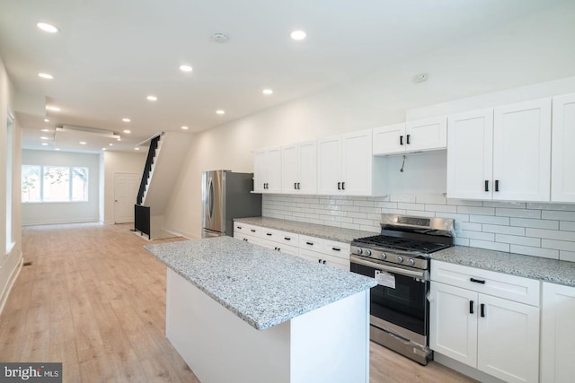 1606 Wharton St, Philadelphia, PA 19146 - kitchen with appliances with stainless steel finishes, a kitchen island, white cabinetry, tasteful backsplash, and light stone countertops