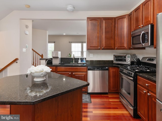 6888 Tasker Fls, Elkridge, MD 21075 - kitchen with stainless steel appliances, light wood-style flooring, dark stone countertops, and a center island