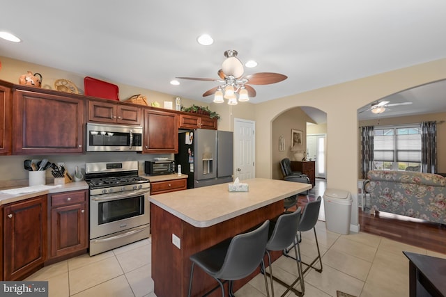 1009 Rosebud St, Reading, PA 19605 - kitchen with appliances with stainless steel finishes, a ceiling fan, arched walkways, light countertops, and a kitchen bar