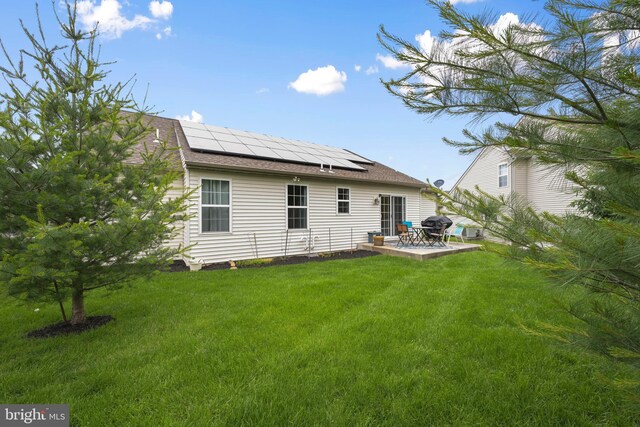1009 Rosebud St, Reading, PA 19605 - rear view of house featuring solar panels, a patio area, a lawn, and a shingled roof