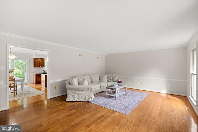 98 Magnificent Ln, Hedgesville, WV 25427 - living room featuring light wood finished floors, crown molding, baseboards, and a chandelier