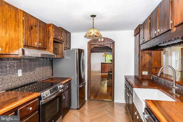 6908 S Roxbury Mill Rd, Spotsylvania, VA 22551 - kitchen with stainless steel appliances, under cabinet range hood, wood counters, a sink, and tasteful backsplash