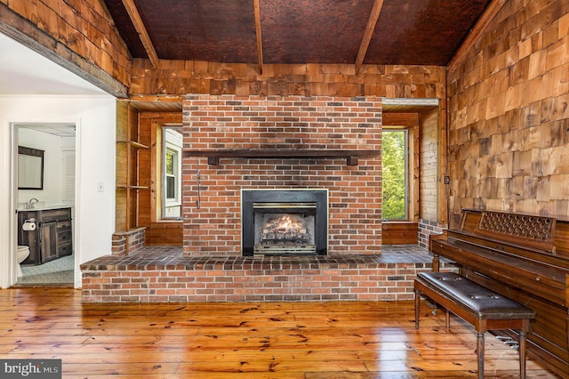 6908 S Roxbury Mill Rd, Spotsylvania, VA 22551 - unfurnished living room with hardwood / wood-style floors, wood walls, a brick fireplace, beamed ceiling, and a sink