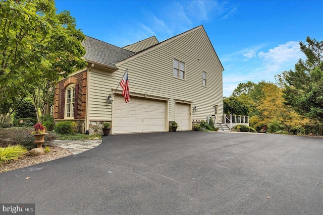 27422 Bridle Pl, Chantilly, VA 20152 - view of property exterior featuring an attached garage, asphalt driveway, stone siding, and roof with shingles