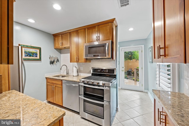 303 N W St, Alexandria, VA 22314 - kitchen with appliances with stainless steel finishes, a sink, decorative backsplash, light stone countertops, and brown cabinetry