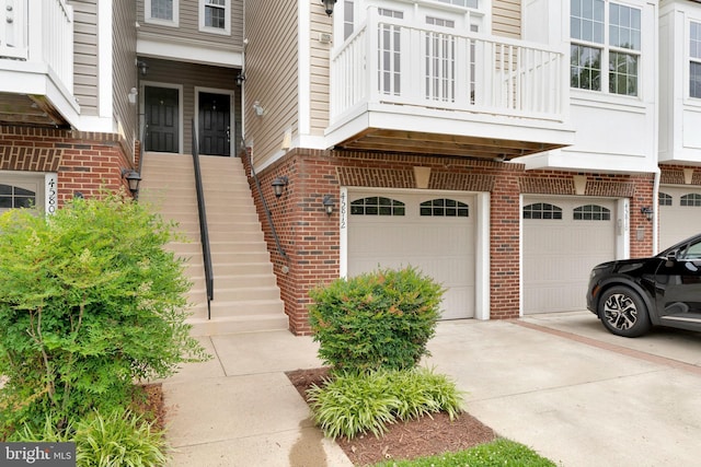 45812 Winding Branch Ter, Sterling, VA 20166 - view of exterior entry featuring driveway, a garage, a balcony, and brick siding