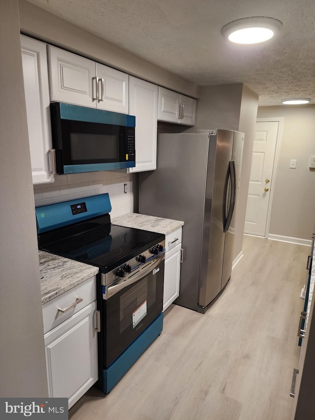 1002 Downing Ct Unit 1002-B, Bel Air, MD 21014 - kitchen with appliances with stainless steel finishes, a textured ceiling, light wood-style flooring, white cabinetry, and tasteful backsplash
