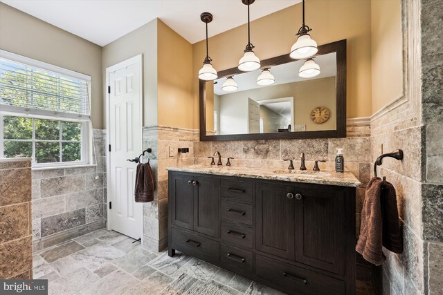 24830 Showbarn Cir, Damascus, MD 20872 - bathroom with tile walls, a wainscoted wall, double vanity, and stone finish flooring