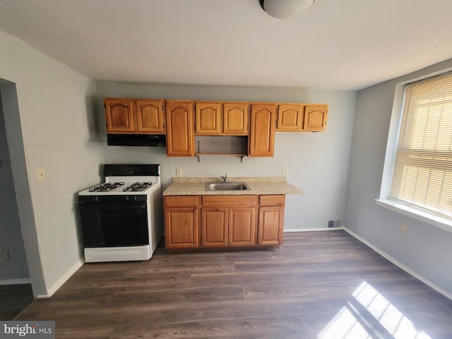 2845 Harlem Ave, Baltimore, MD 21216 - kitchen featuring range with gas cooktop, under cabinet range hood, a sink, light countertops, and dark wood finished floors
