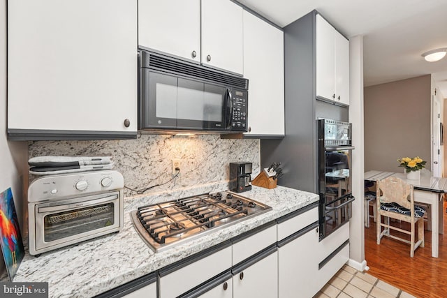 6901 Valley Ave Unit H2, Philadelphia, PA 19128 - kitchen with black appliances, white cabinetry, a warming drawer, tasteful backsplash, and light stone countertops