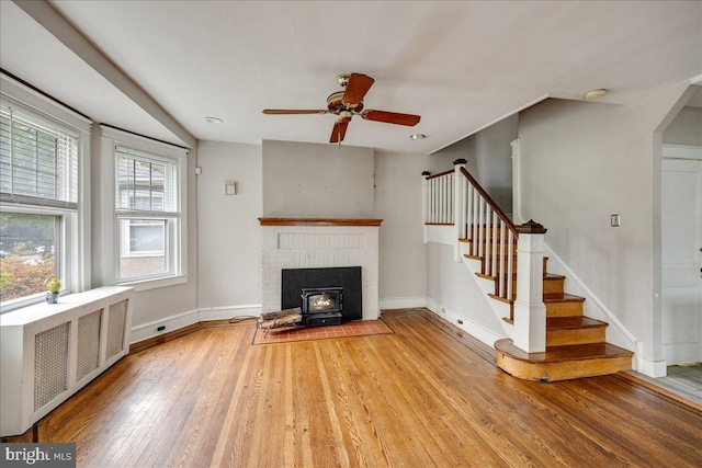 344 Clearbrook Ave, Lansdowne, PA 19050 - unfurnished living room featuring radiator, a wood stove, stairway, light wood-style flooring, and ceiling fan
