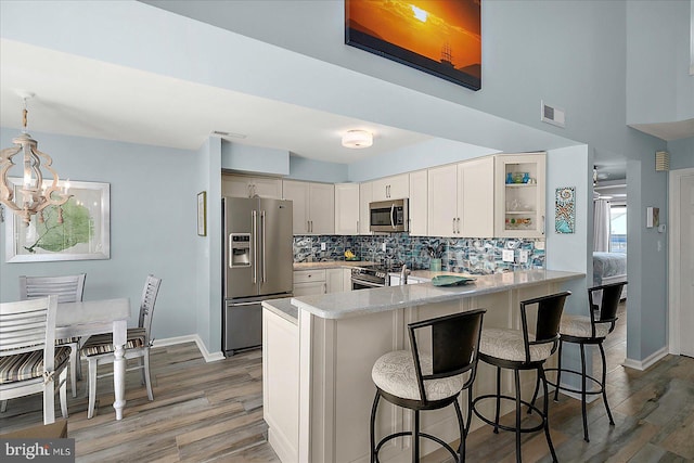 39724 E Sun Dr Unit 226, Fenwick Island, DE 19944 - kitchen with stainless steel appliances, a peninsula, light wood-style flooring, decorative backsplash, and light countertops