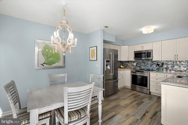 39724 E Sun Dr Unit 226, Fenwick Island, DE 19944 - kitchen with appliances with stainless steel finishes, a chandelier, dark wood finished floors, tasteful backsplash, and light countertops