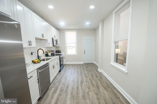 2116 E Hoffman St, Baltimore, MD 21213 - kitchen with stainless steel appliances, light wood-style floors, backsplash, white cabinetry, and recessed lighting