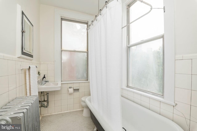 2638 E Baltimore St, Baltimore, MD 21224 - bathroom with radiator, tile walls, toilet, a wainscoted wall, and tile patterned floors