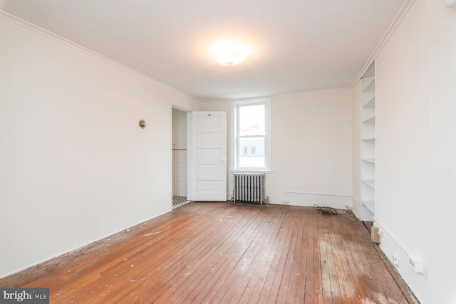 2638 E Baltimore St, Baltimore, MD 21224 - spare room featuring radiator heating unit, wood-type flooring, and ornamental molding