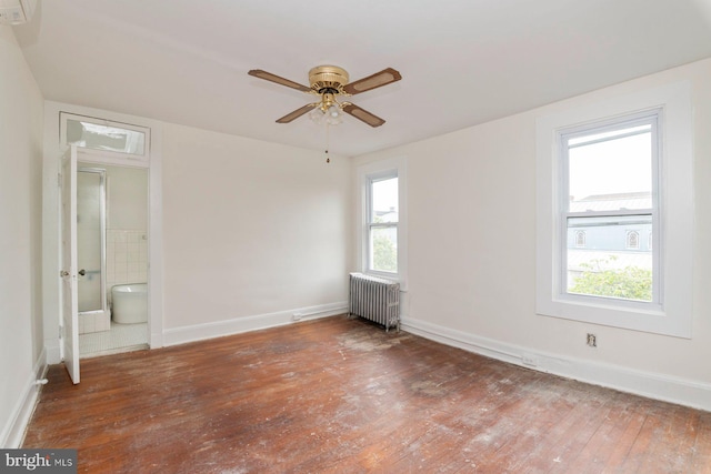 2638 E Baltimore St, Baltimore, MD 21224 - unfurnished bedroom featuring radiator heating unit, hardwood / wood-style flooring, multiple windows, and baseboards