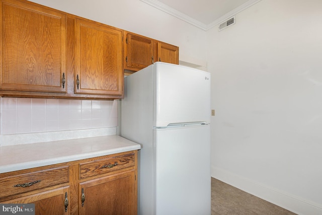 212 S Union Ave, Havre De Grace, MD 21078 - kitchen featuring freestanding refrigerator, backsplash, brown cabinetry, light countertops, and crown molding