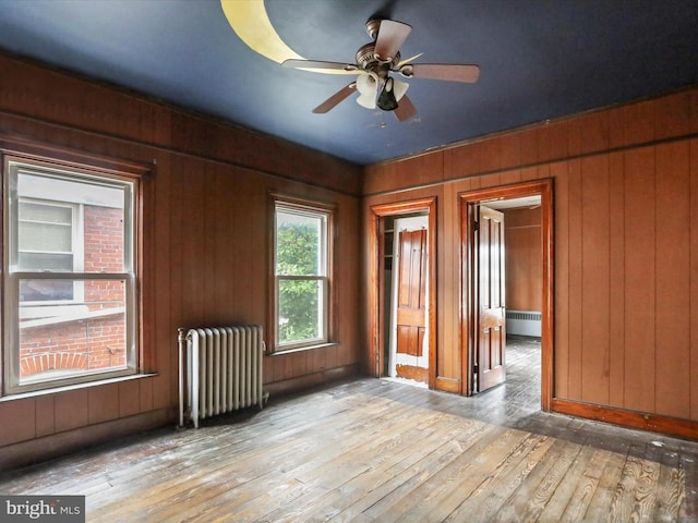 16 Avalon Ave, Hagerstown, MD 21740 - empty room featuring radiator heating unit, radiator, hardwood / wood-style floors, wood walls, and a ceiling fan